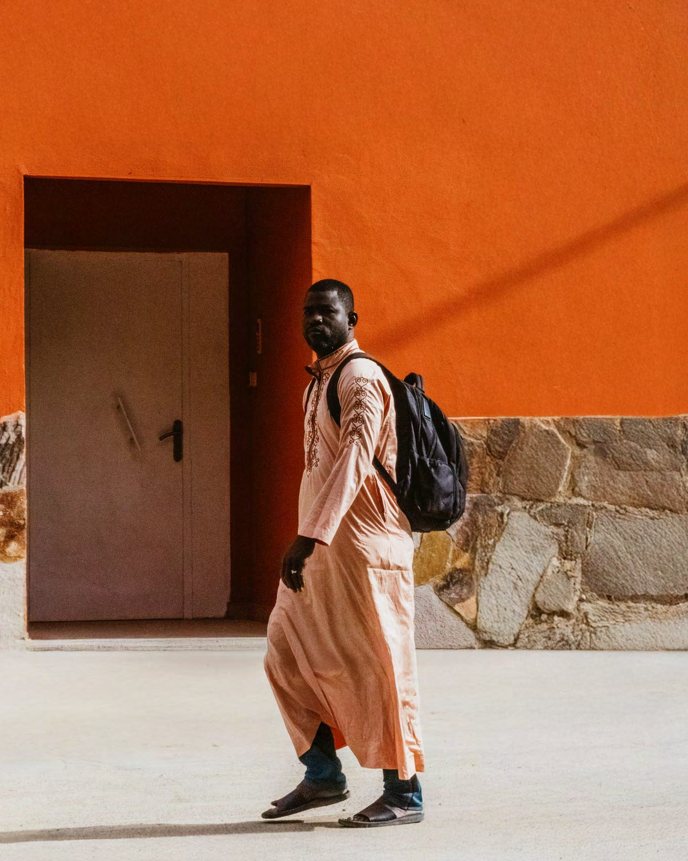 Passing figure, orange wall — Psycho Moustache
